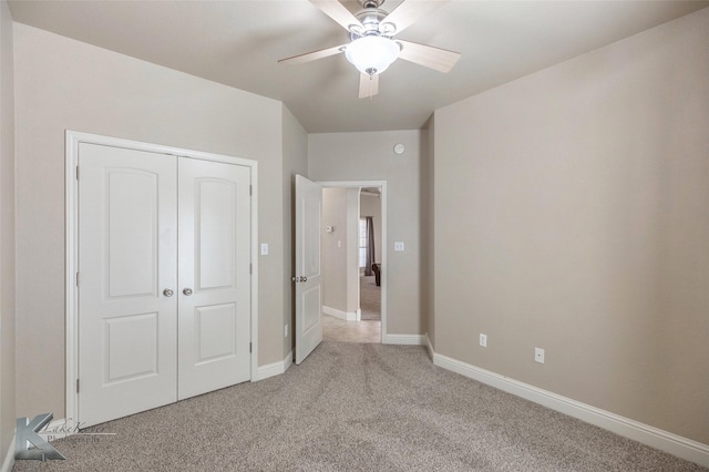 unfurnished bedroom featuring a closet, light colored carpet, ceiling fan, and baseboards