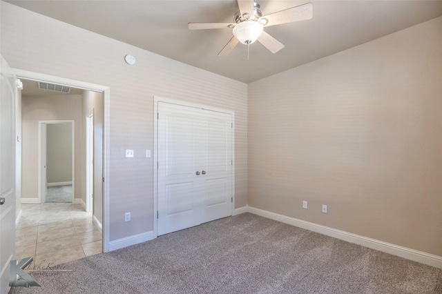 unfurnished bedroom featuring ceiling fan, light tile patterned flooring, light colored carpet, visible vents, and baseboards