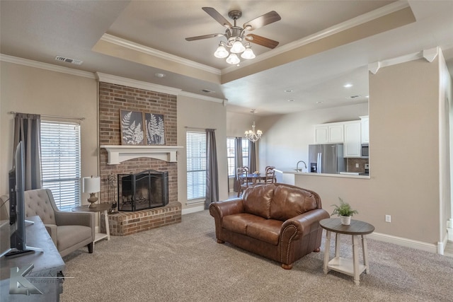 living room with visible vents, ornamental molding, a tray ceiling, carpet floors, and a brick fireplace