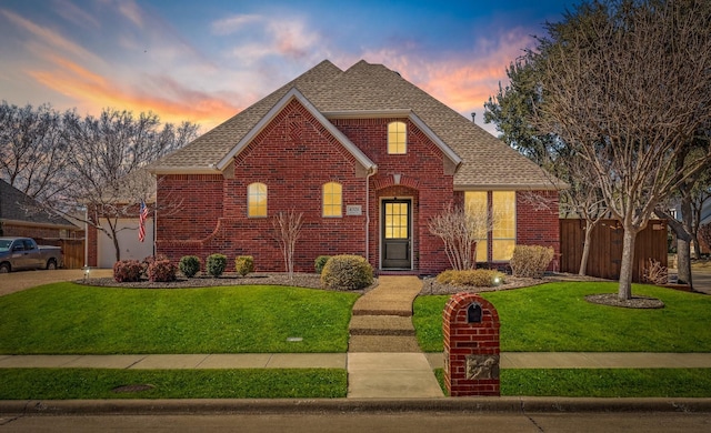 view of front of property with a front yard, brick siding, fence, and roof with shingles