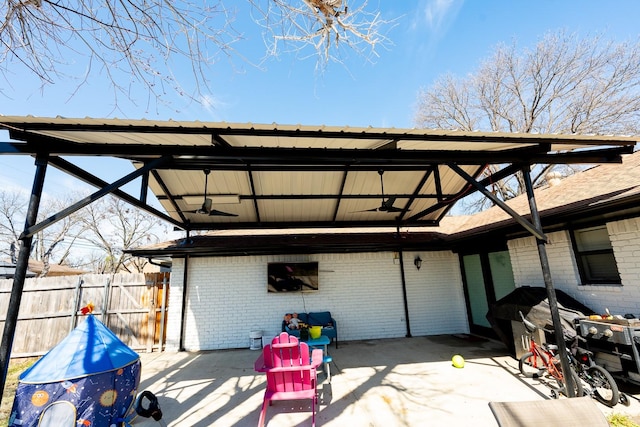 back of house featuring a carport, brick siding, a patio area, and fence