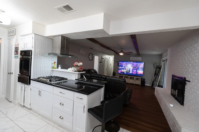 kitchen with visible vents, oven, wall chimney range hood, stainless steel gas stovetop, and a warming drawer