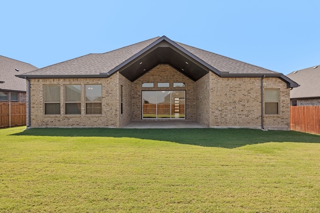 rear view of house featuring fence private yard, brick siding, a patio, and a yard