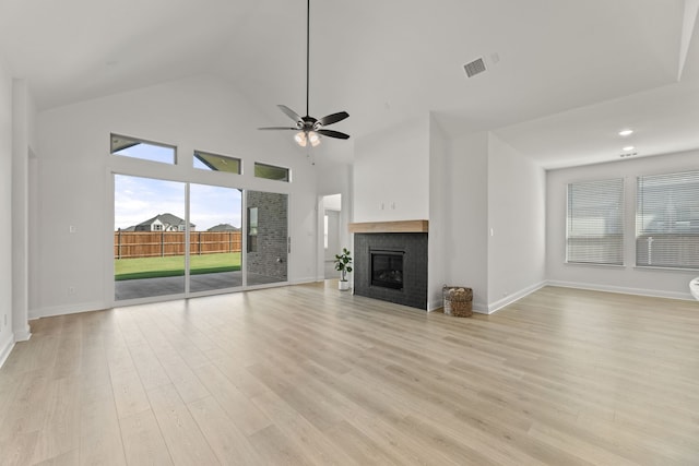 unfurnished living room featuring visible vents, a ceiling fan, light wood-style floors, a fireplace, and high vaulted ceiling