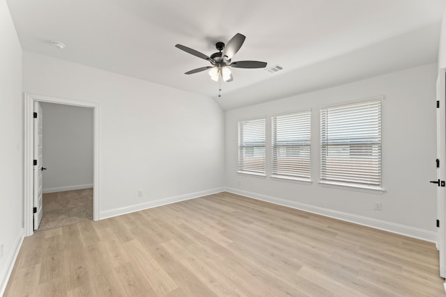 empty room featuring light wood finished floors, lofted ceiling, visible vents, ceiling fan, and baseboards