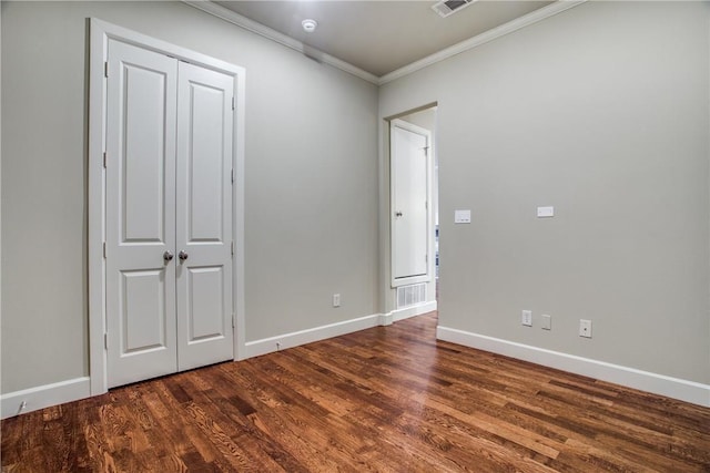 unfurnished bedroom with dark wood-type flooring, visible vents, ornamental molding, and baseboards