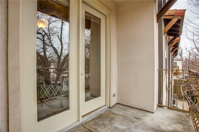 view of exterior entry featuring a balcony and stucco siding