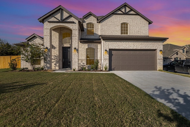 french country home featuring an attached garage, brick siding, fence, driveway, and a front lawn