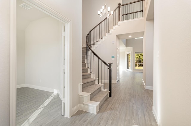 stairs featuring a towering ceiling, baseboards, and wood finished floors