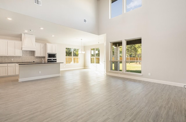 unfurnished living room featuring light wood finished floors, baseboards, and visible vents