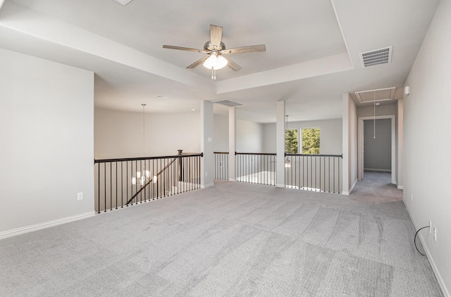 spare room with carpet, attic access, visible vents, and a raised ceiling