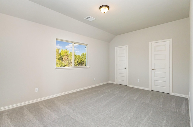 unfurnished bedroom with vaulted ceiling, carpet, visible vents, and baseboards