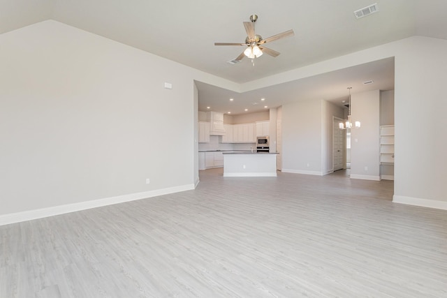 unfurnished living room with light wood-type flooring, visible vents, baseboards, and ceiling fan with notable chandelier