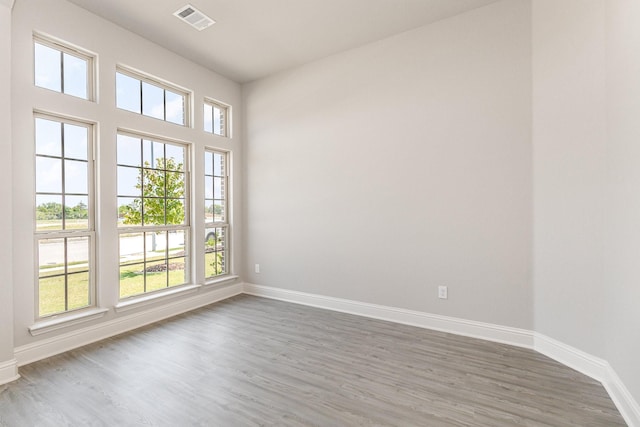 empty room featuring wood finished floors, visible vents, and baseboards