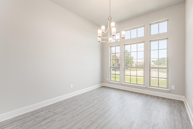 unfurnished room with baseboards, a chandelier, and wood finished floors