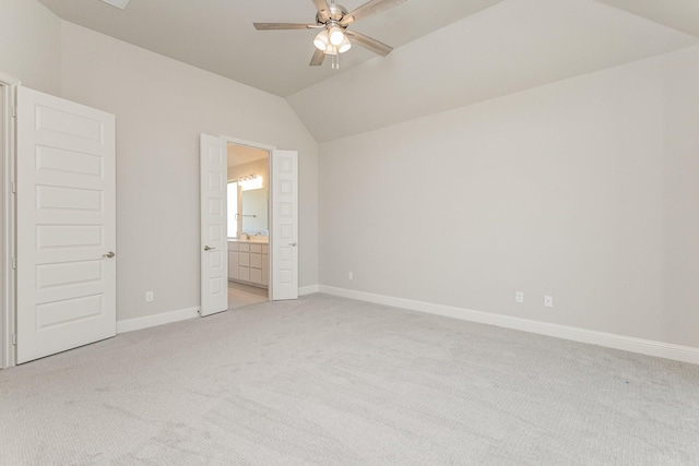 unfurnished bedroom featuring ensuite bathroom, lofted ceiling, light carpet, a ceiling fan, and baseboards