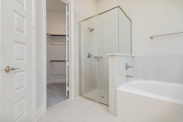 bathroom with a garden tub, a shower stall, and a spacious closet