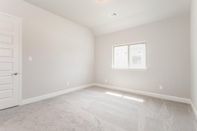 unfurnished room with light carpet, baseboards, visible vents, and vaulted ceiling