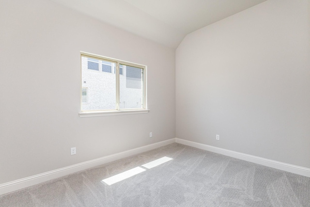 spare room featuring carpet flooring, vaulted ceiling, and baseboards