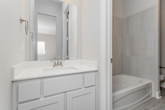 bathroom featuring wood finished floors, bathtub / shower combination, vanity, and toilet