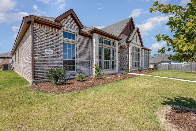 view of front of home featuring brick siding, a front yard, fence, and central air condition unit