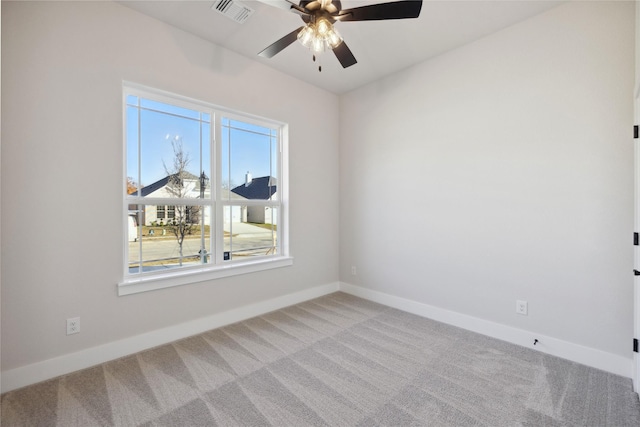 carpeted empty room with a ceiling fan, visible vents, and baseboards