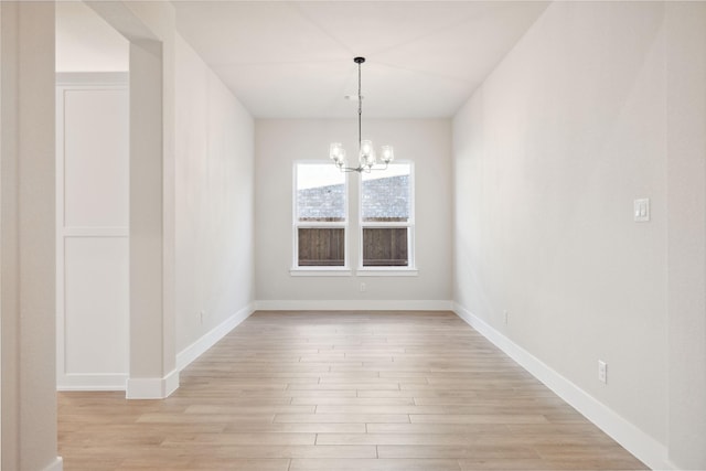 unfurnished dining area with light wood-type flooring, baseboards, and a chandelier