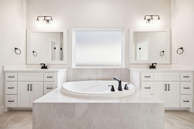 bathroom featuring a garden tub, two vanities, and a sink