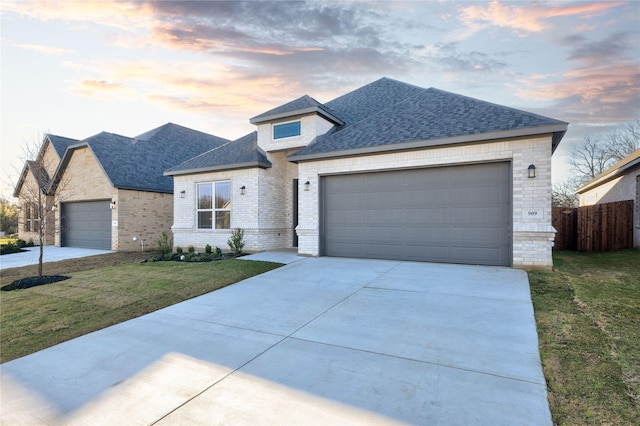 view of front facade with driveway, a garage, a lawn, and brick siding