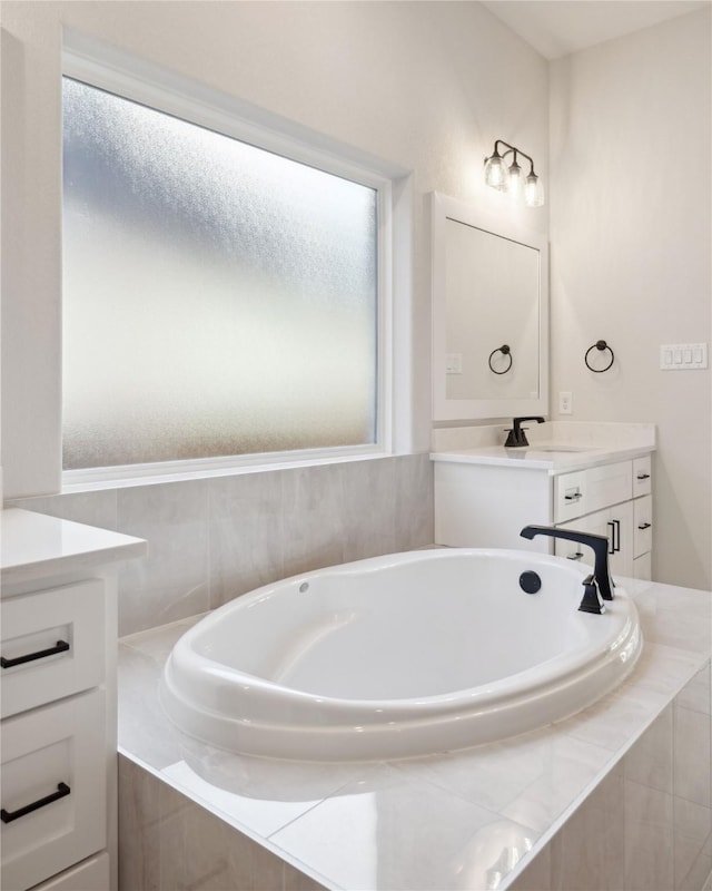 bathroom featuring a healthy amount of sunlight, a garden tub, and vanity