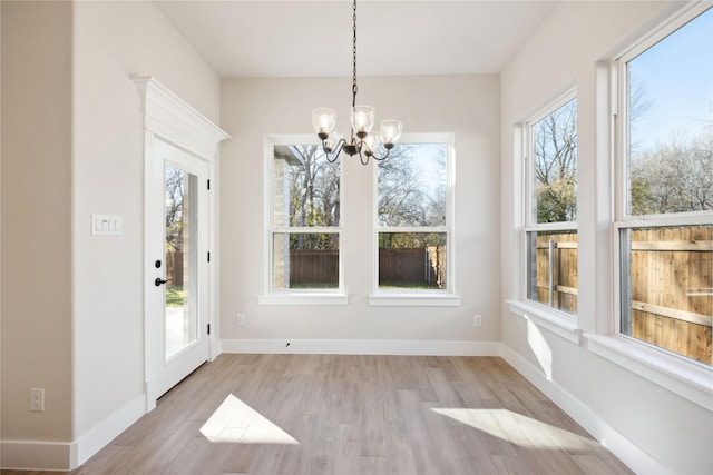 interior space with a chandelier, a healthy amount of sunlight, baseboards, and wood finished floors