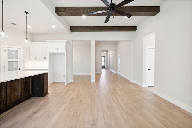 unfurnished living room featuring baseboards, beamed ceiling, and light wood finished floors