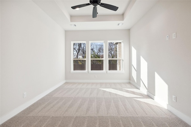 empty room with carpet floors, baseboards, visible vents, and a raised ceiling