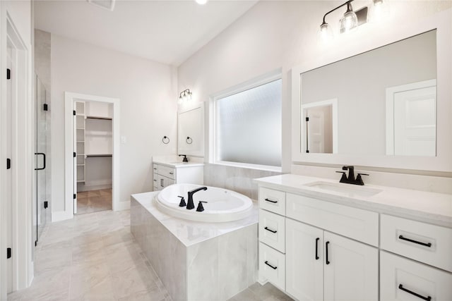 bathroom featuring two vanities, a spacious closet, a stall shower, a sink, and a bath