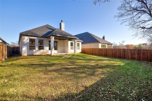 rear view of house featuring a yard, a fenced backyard, brick siding, and central AC