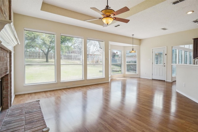 unfurnished living room with a brick fireplace, visible vents, and wood finished floors