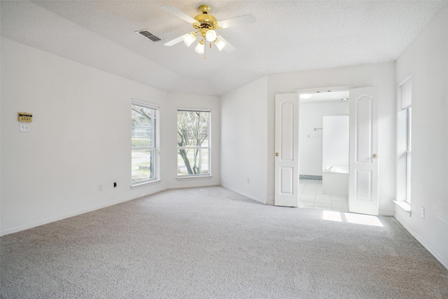 carpeted empty room featuring a textured ceiling, baseboards, visible vents, and a ceiling fan