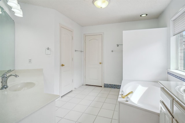 bathroom featuring a textured ceiling, a garden tub, two vanities, a sink, and tile patterned floors