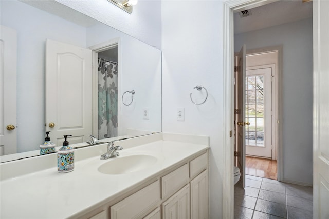 full bathroom with toilet, vanity, visible vents, and tile patterned floors