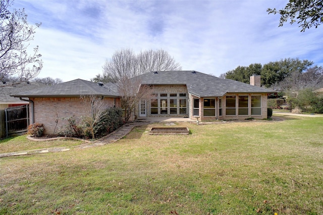 rear view of property with a sunroom, a chimney, fence, a yard, and brick siding