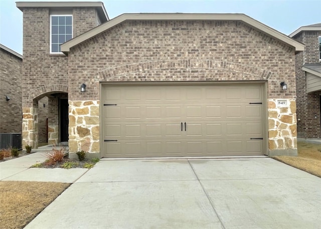 garage with concrete driveway and central air condition unit