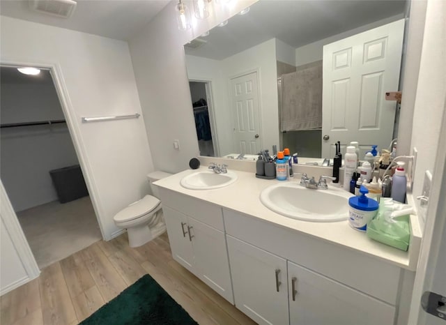 full bath featuring double vanity, wood finished floors, walk in shower, and a sink