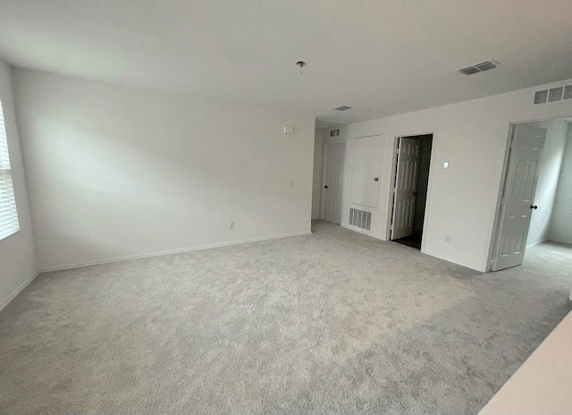 unfurnished bedroom featuring baseboards, visible vents, and light colored carpet