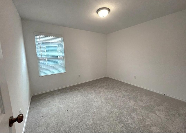 carpeted spare room featuring baseboards