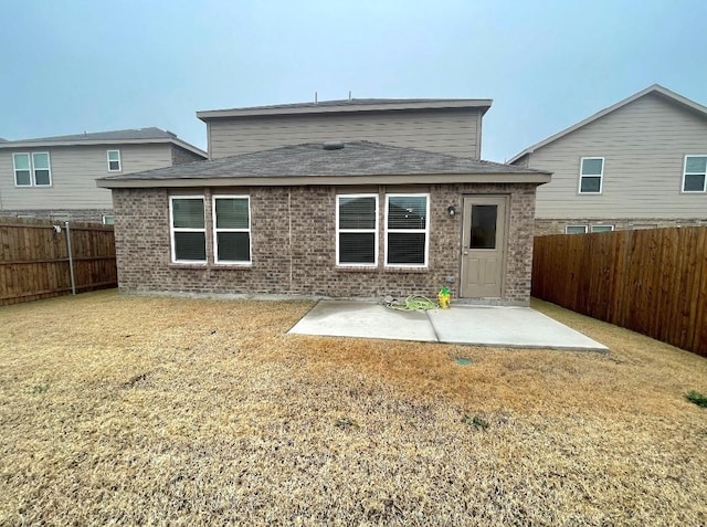 rear view of property with a patio area, a fenced backyard, a yard, and brick siding