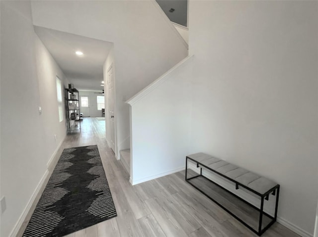 hallway featuring light wood finished floors and baseboards