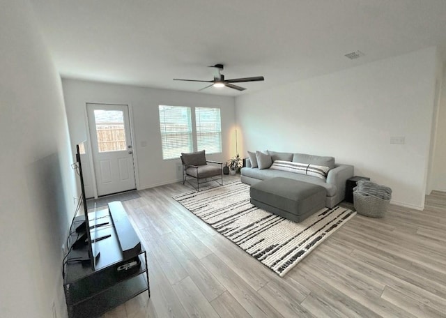 living area featuring light wood finished floors, baseboards, visible vents, and a ceiling fan