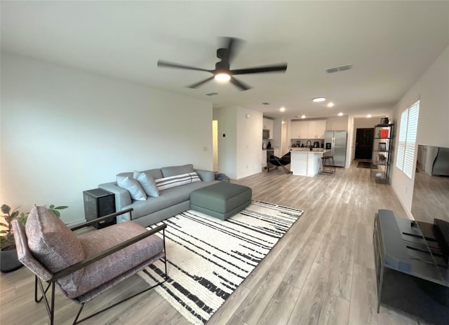 living room with visible vents, baseboards, light wood-style flooring, ceiling fan, and recessed lighting