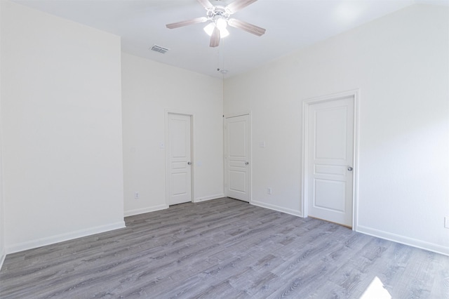 empty room featuring visible vents, ceiling fan, baseboards, and wood finished floors