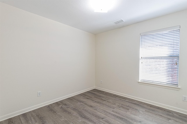 empty room with visible vents, baseboards, and wood finished floors